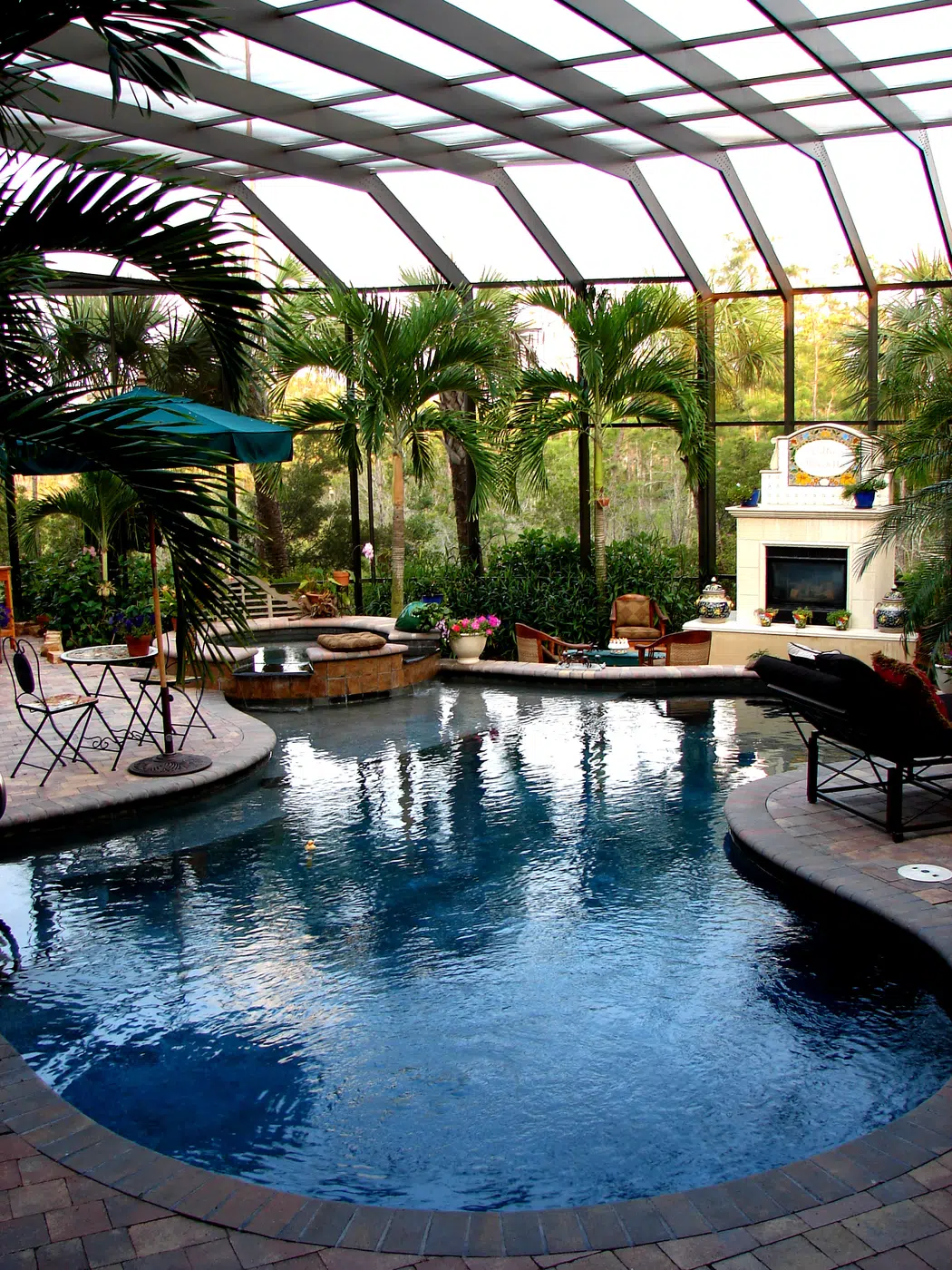 Tropical hotel courtyard swimming pool with loungers and fireplace