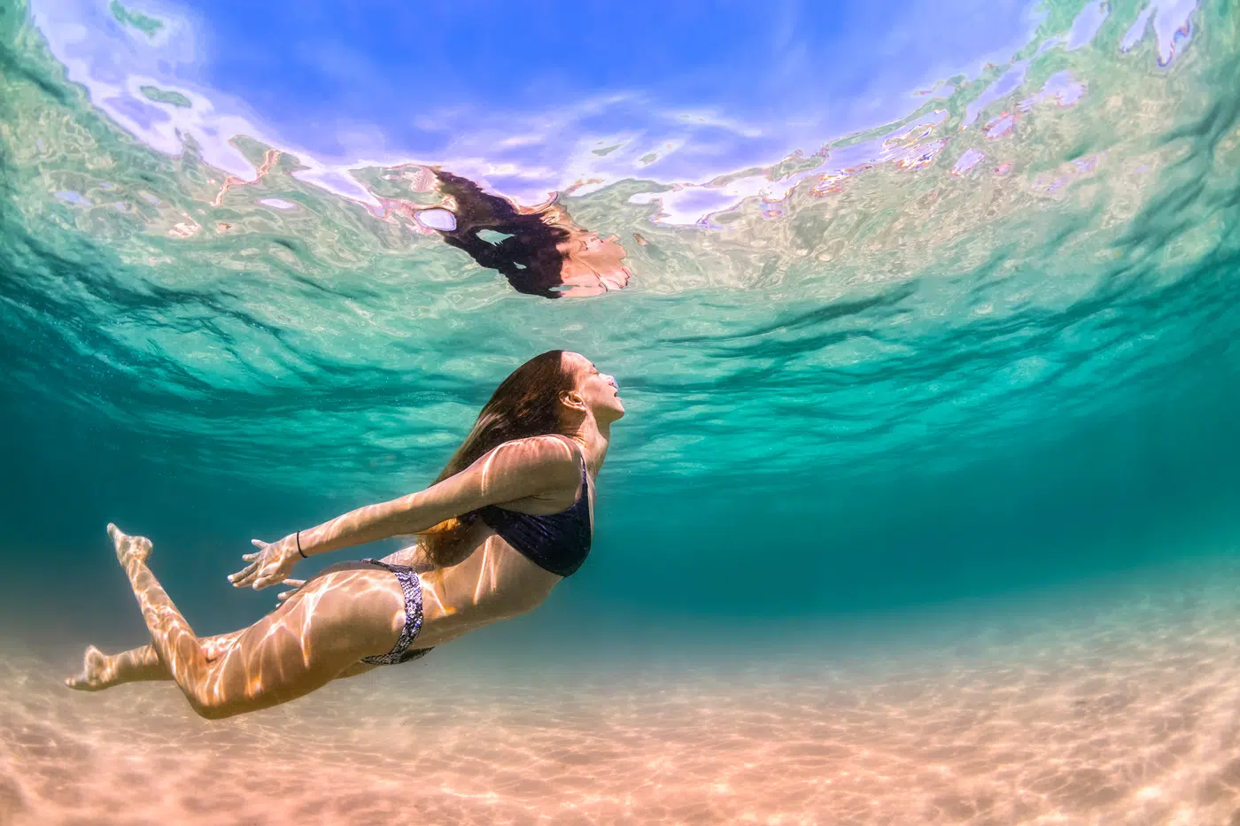 Split underwater view of crystal-clear turquoise swimming water