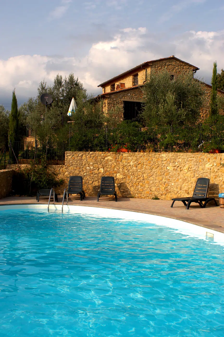 Architectural stone-walled courtyard swimming pool with sun loungers